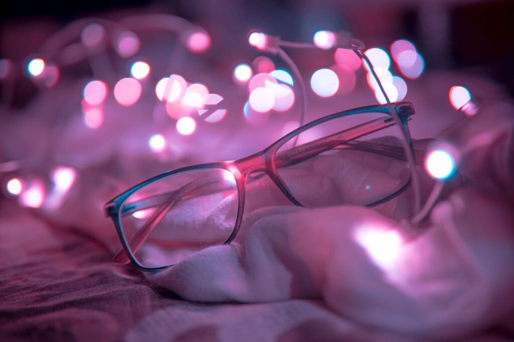 pexels photo 668351 Close-up of eyeglasses resting among glowing pink bokeh lights on soft fabric.